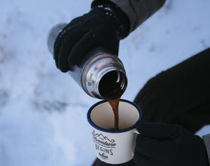 portable coffee maker pouring mug of coffee in snow